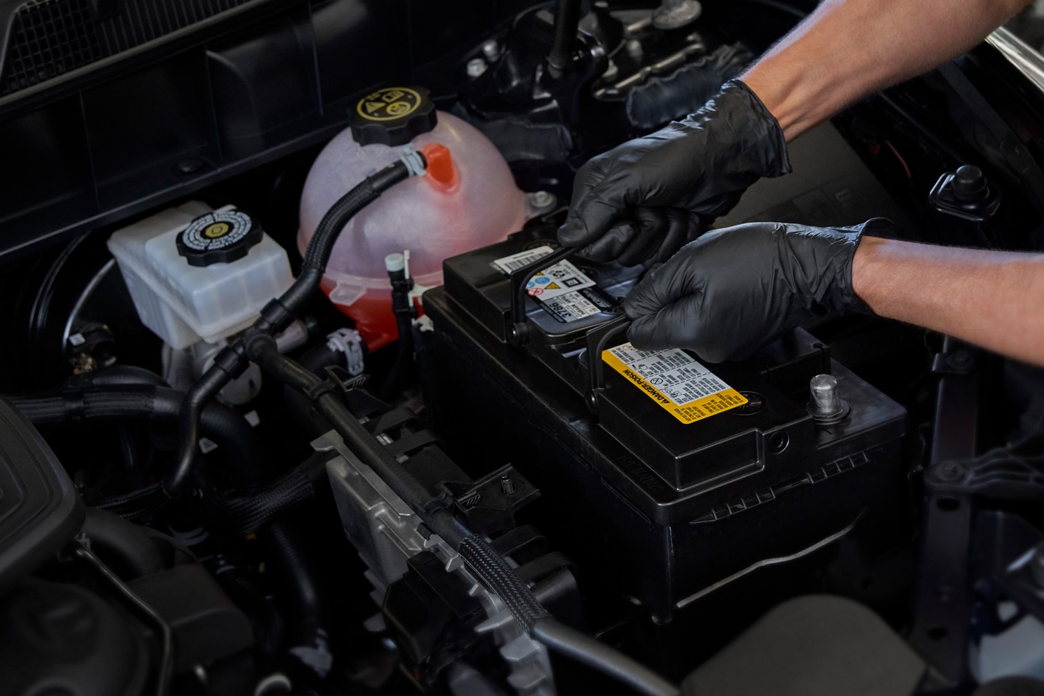 A battery is being placed into a car's engine compartment
