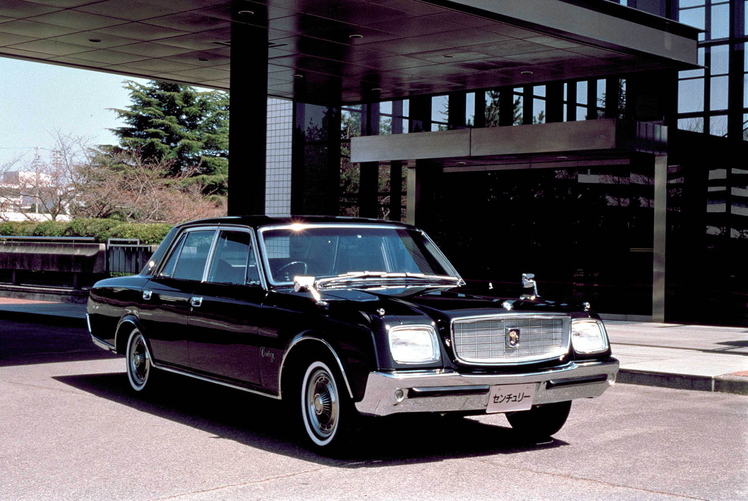 1967 Toyota Century in black in front of a glass-and-steel building