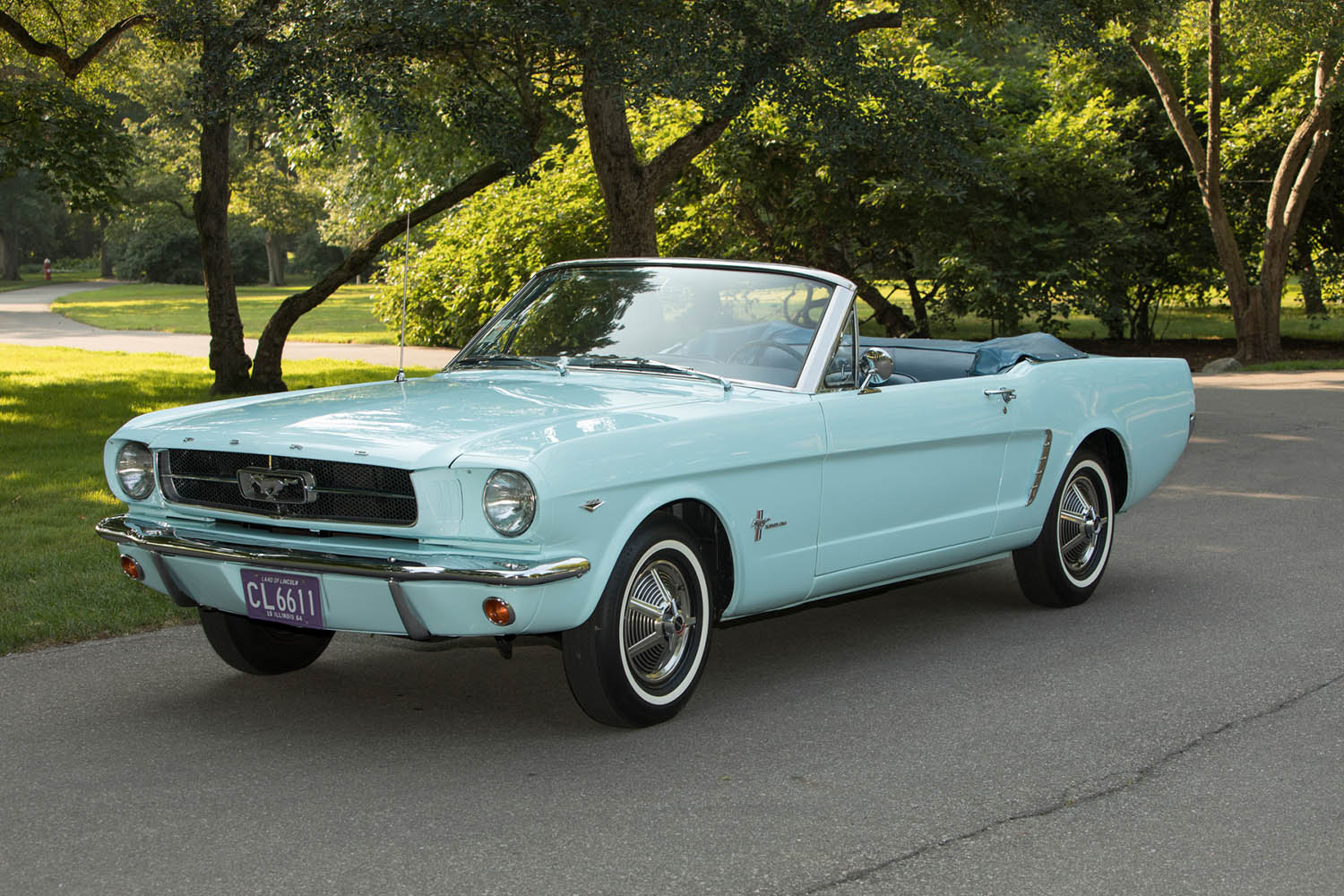 1960s-era Ford Mustang in aqua parked in front of trees