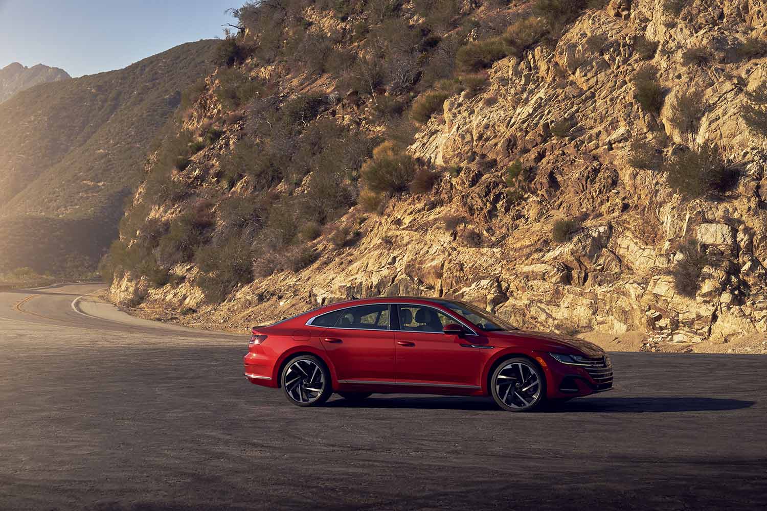 2021 Volkswagen Arteon in red driving on a road next to mountains
