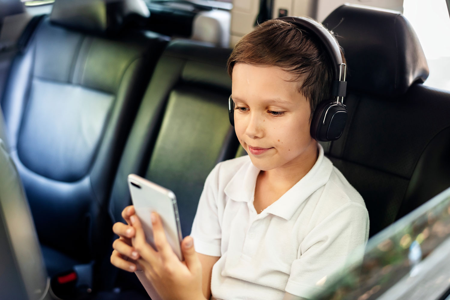 Child using phone in car with headphones
