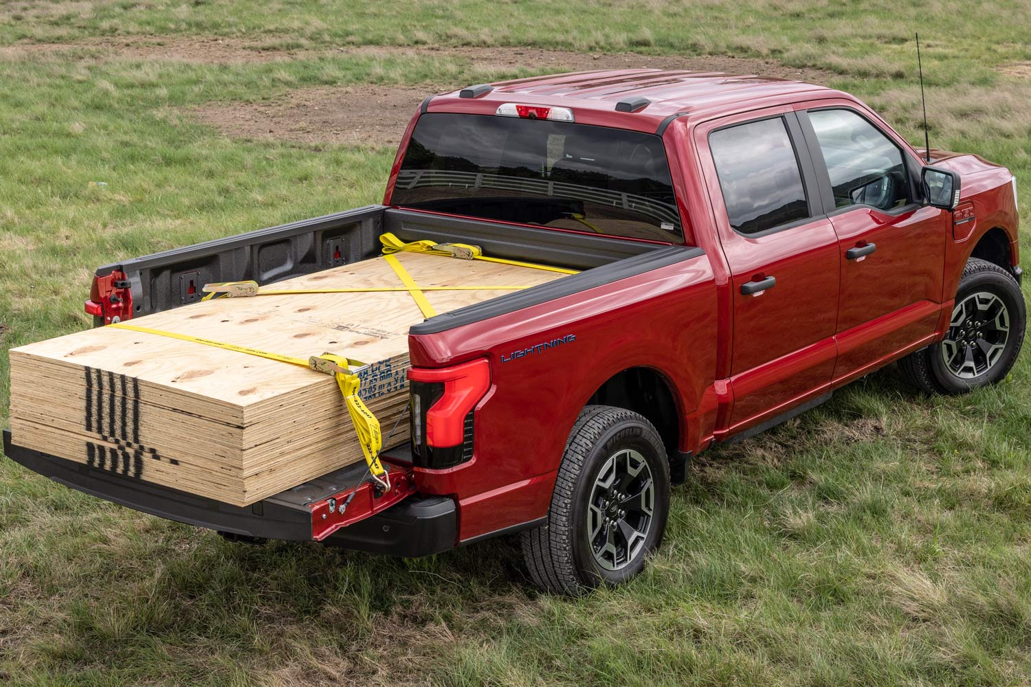 Ford F-150 Lightning hauling a payload of plywood strapped in bed