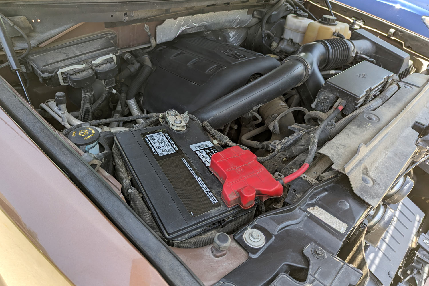 Battery under hood of brown pickup truck.
