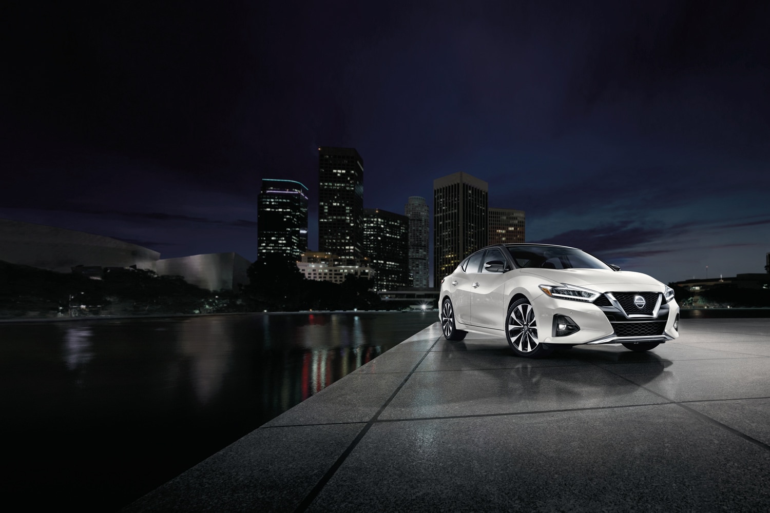 2023 Nissan Maxima in Pearl White TriCoat parked by a reflecting pool in downtown Los Angeles