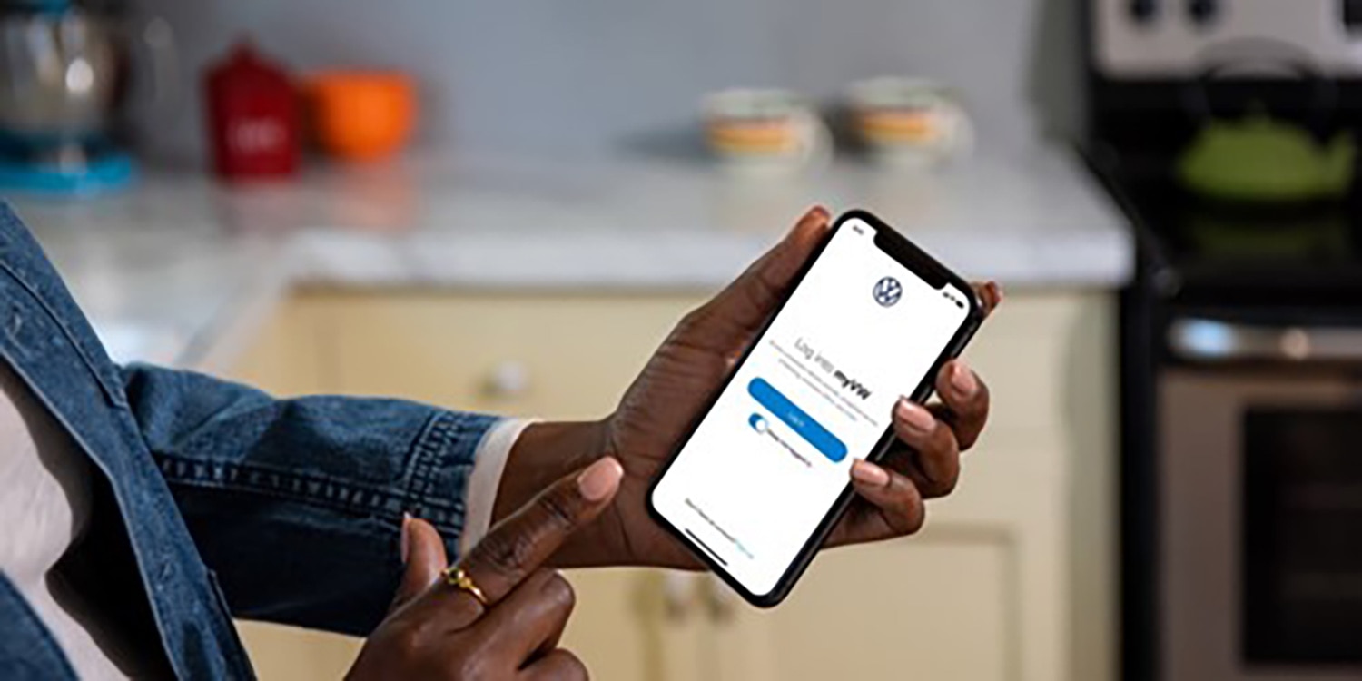 A hand holding a smartphone ready to log into the myVW app