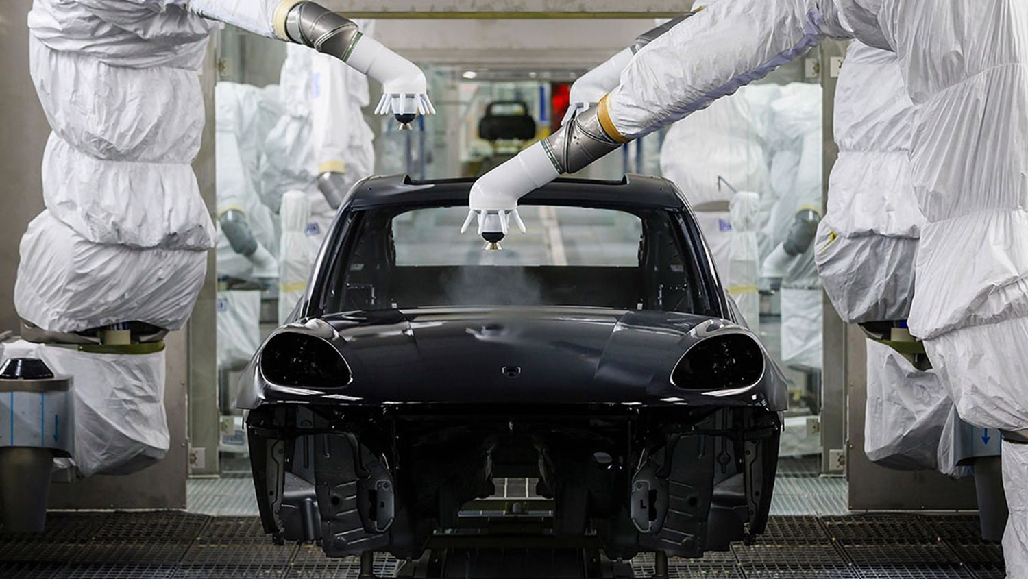 Machines spraying black paint onto an SUV body at Porsche's paint shop in Leipzig, Germany