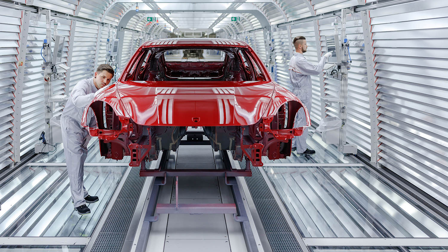 Two technicians examining red paint on a car body in Porsche's Leipzig, Germany, paint shop