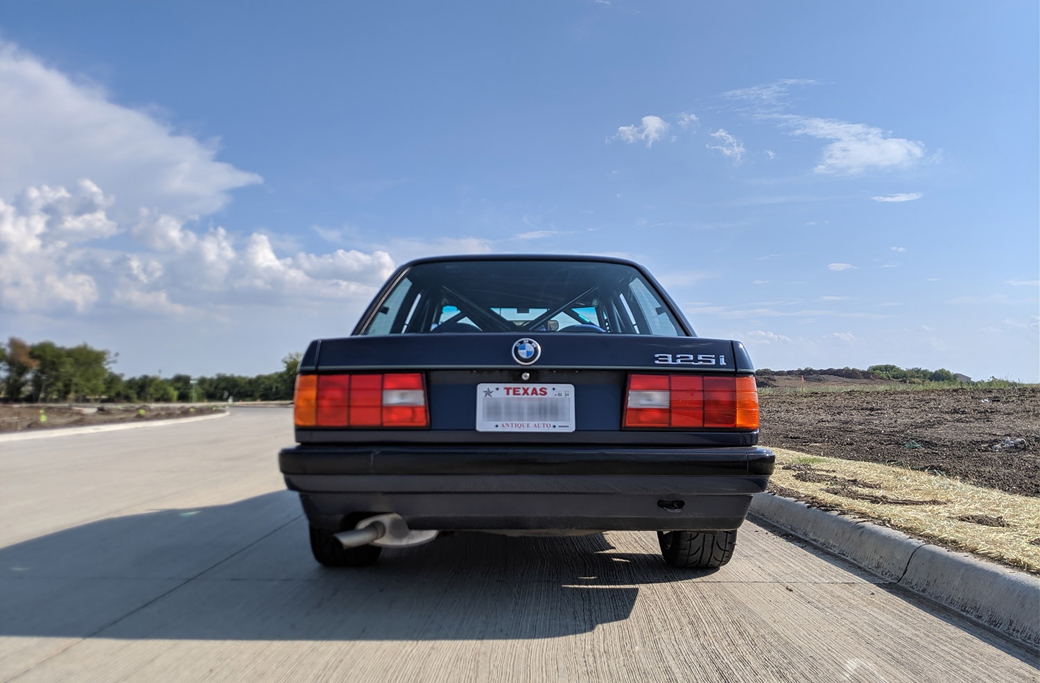The rear view of a second-generation BMW 3 Series in dark blue with a Texas antique auto license plate