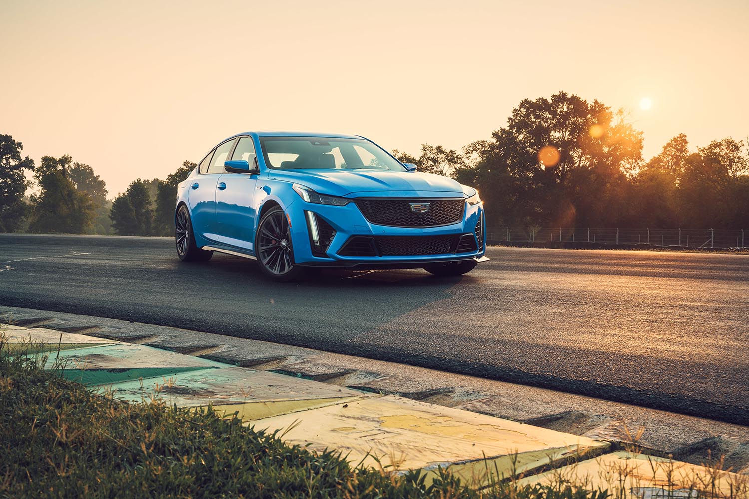 2023 Cadillac CT5-V Blackwing in Electric Blue parked on a raceway curve during early golden hour