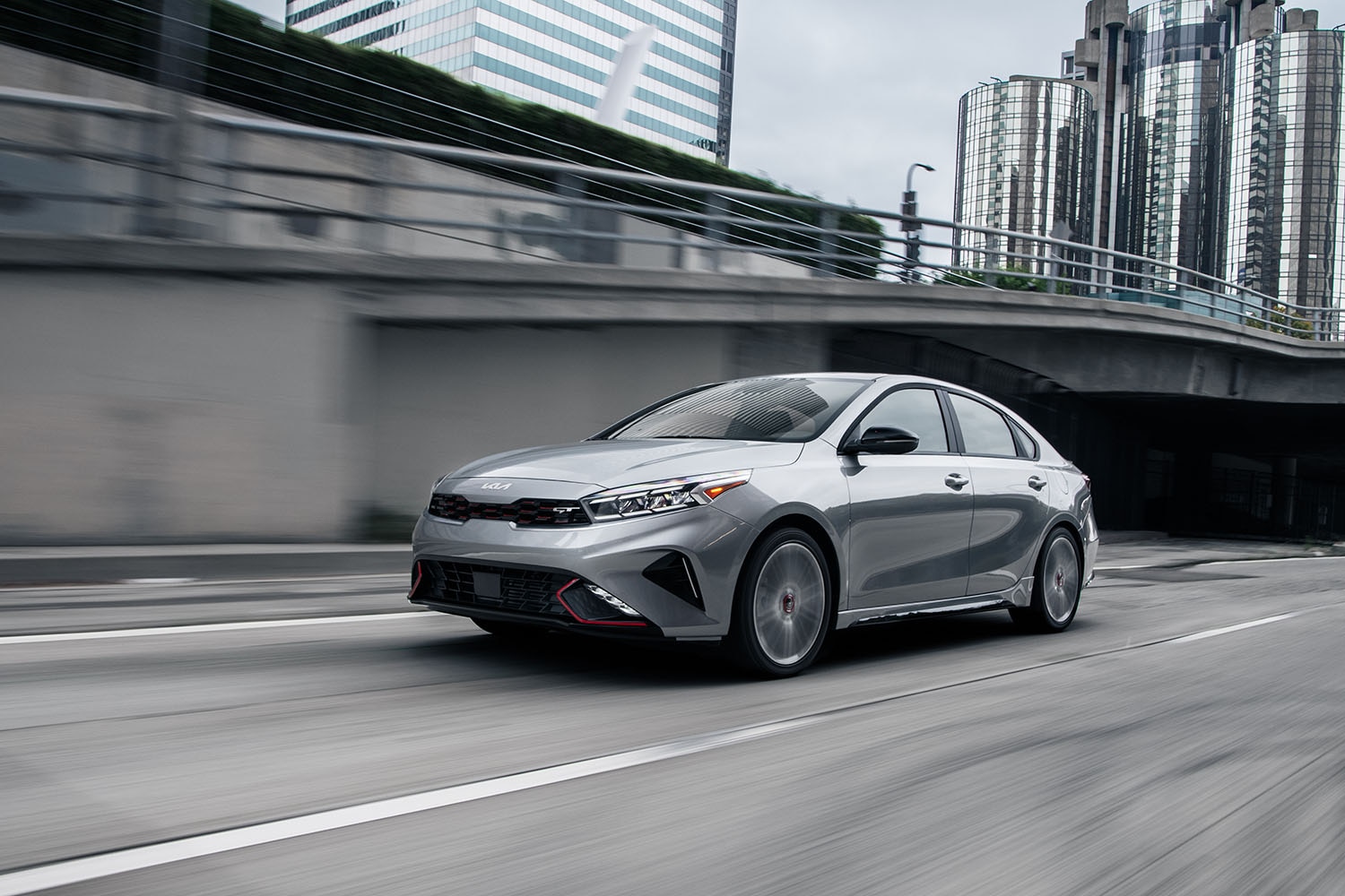 2023 Kia Forte GT in gray driving through a concrete-heavy cityscape in downtown Los Angeles