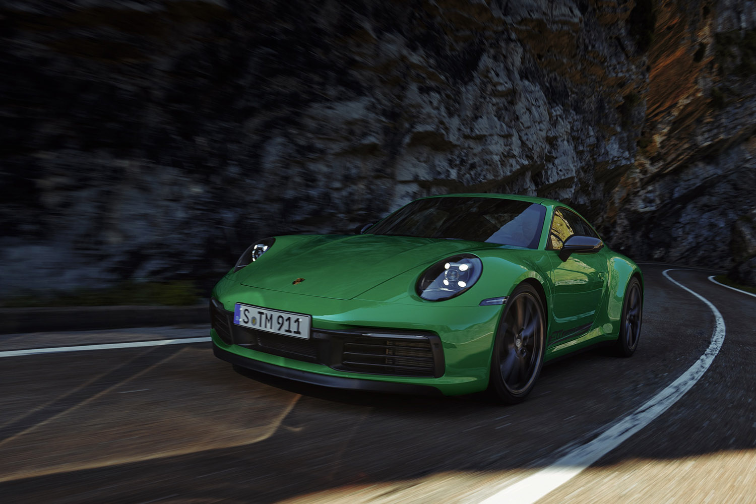 Porsche 911 Carrera T in Python Green navigating out of an S-curve with cliff faces on either side