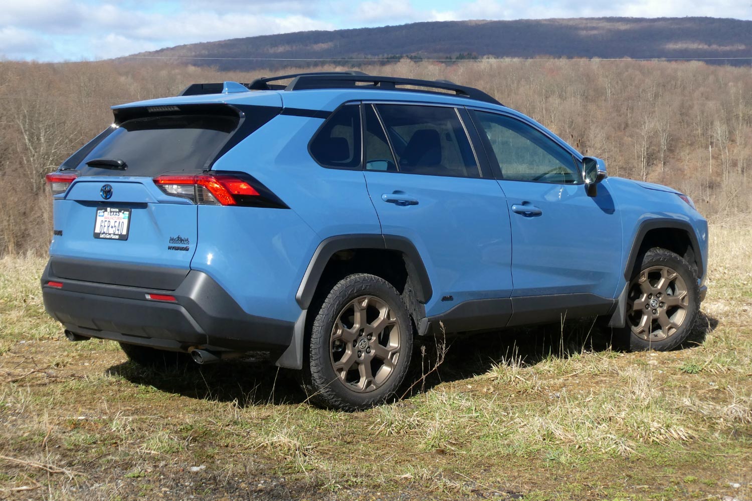 2023 Toyota RAV4 Hybrid Woodland Edition in Cavalry Blue rear angle parked in grass