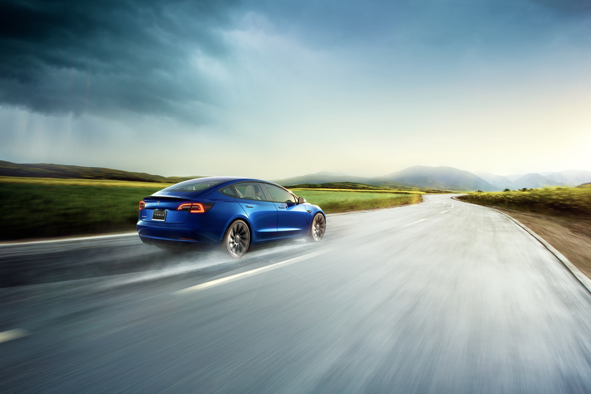 Blue Tesla Model 3 driving down highway