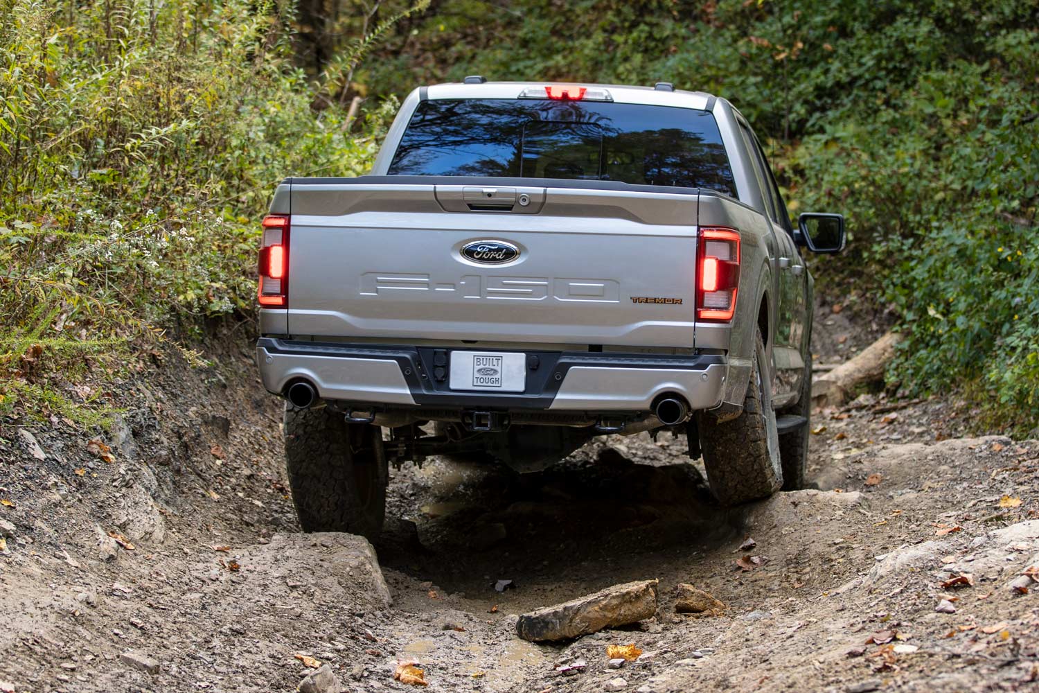  A silver 2023 Ford F-150 Tremor driving up a challenging trail