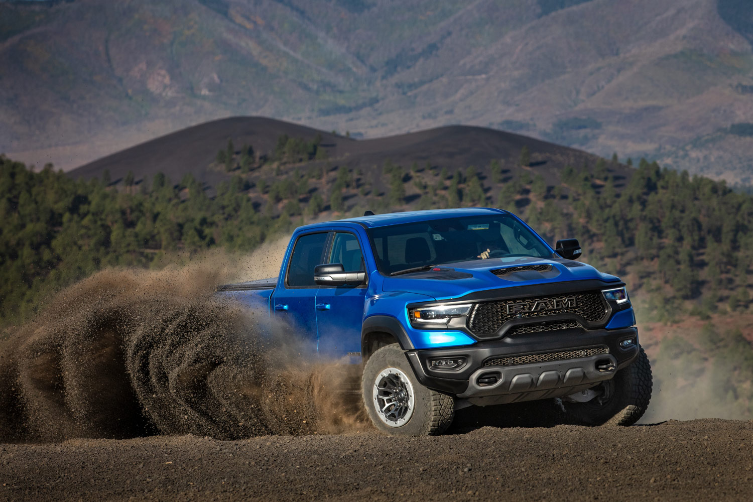 text: 2023 Ram 1500 TRX in blue driving aggressively on dirt