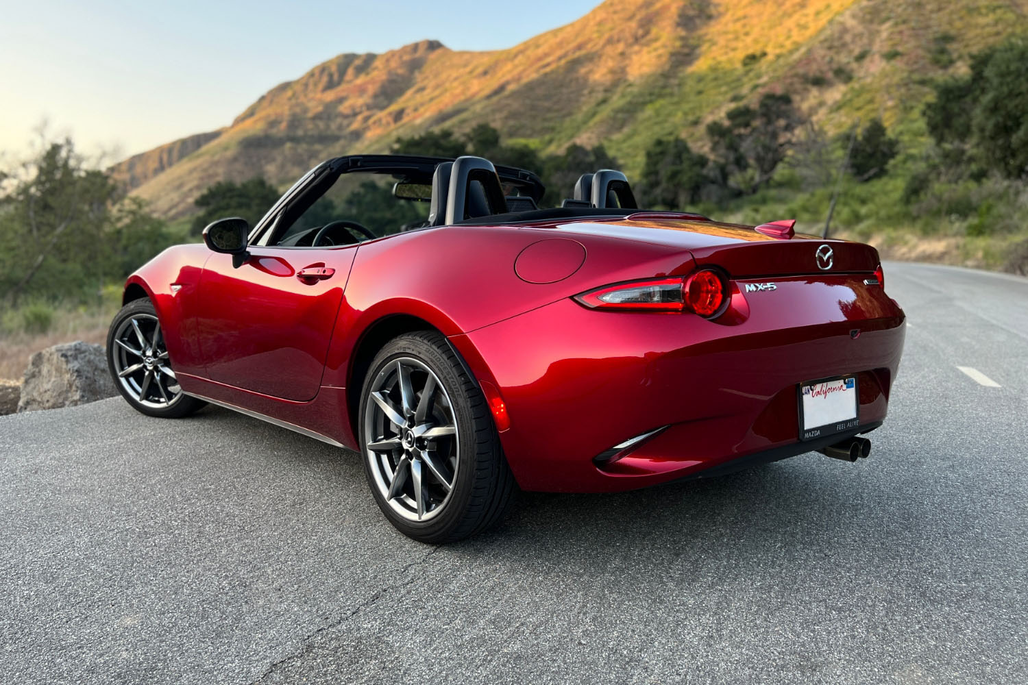 Rear three-quarter shot of a 2023 Mazda MX-5 Miata in Soul Red parked on a winding canyon road
