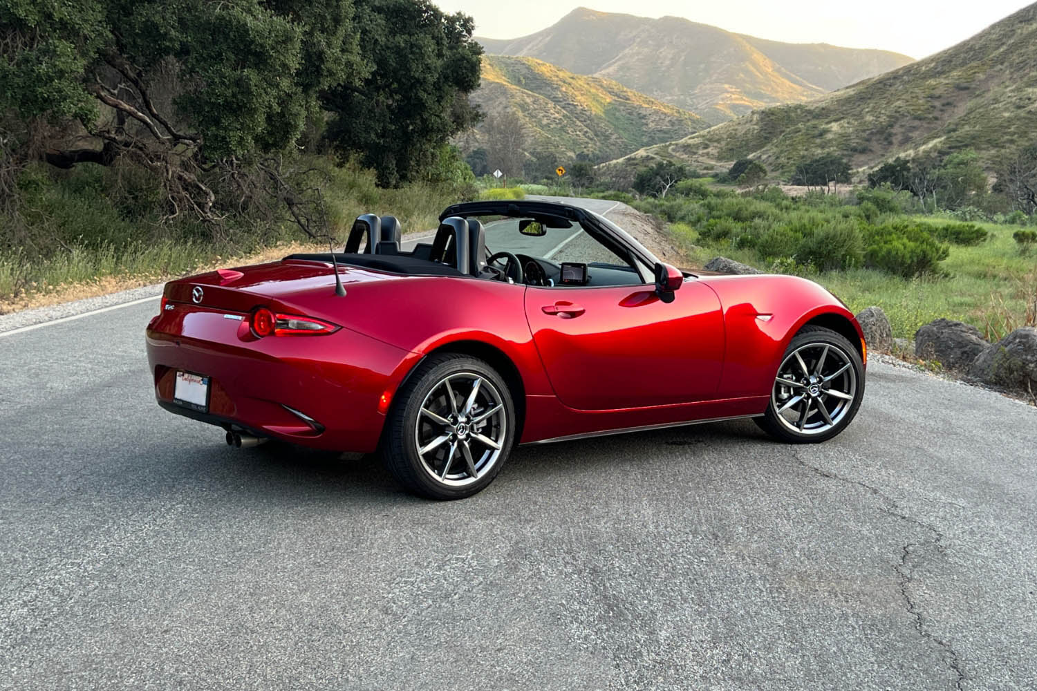 Rear three-quarter shot of a 2023 Mazda MX-5 Miata in Soul Red parked to the side of a narrow canyon road