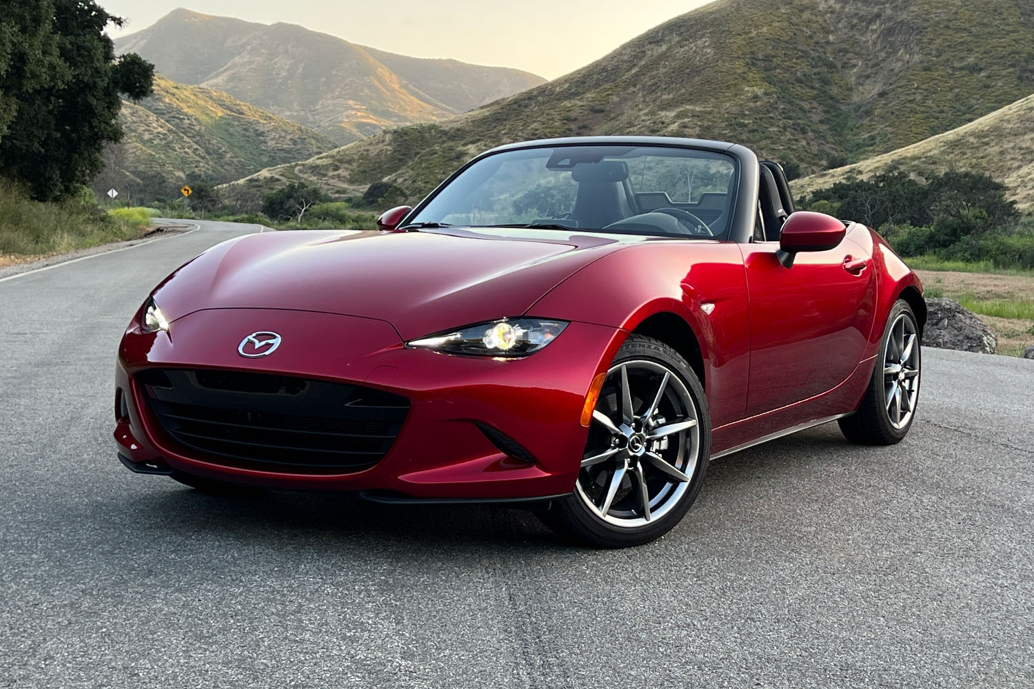 Front three-quarter shot of a 2023 Mazda MX-5 Miata in Soul Red parked to the side of a narrow canyon road