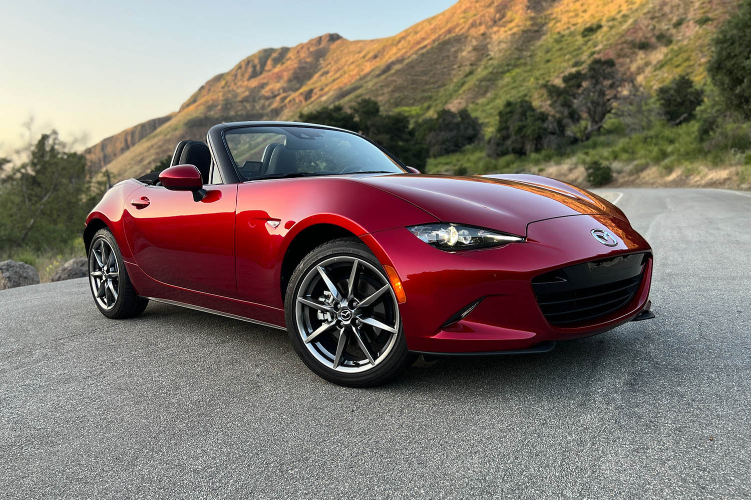 Front three-quarter shot of a 2023 Mazda MX-5 Miata in Soul Red parked on a winding canyon road