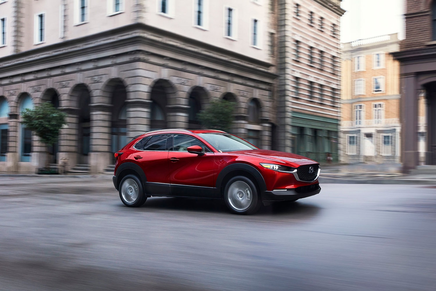 Red 2023 Mazda CX-30 driving on a city street