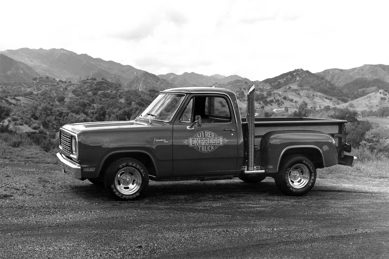 black and white photo of 1979 Dodge Li'l Red Express truck parked on dirt by hills
