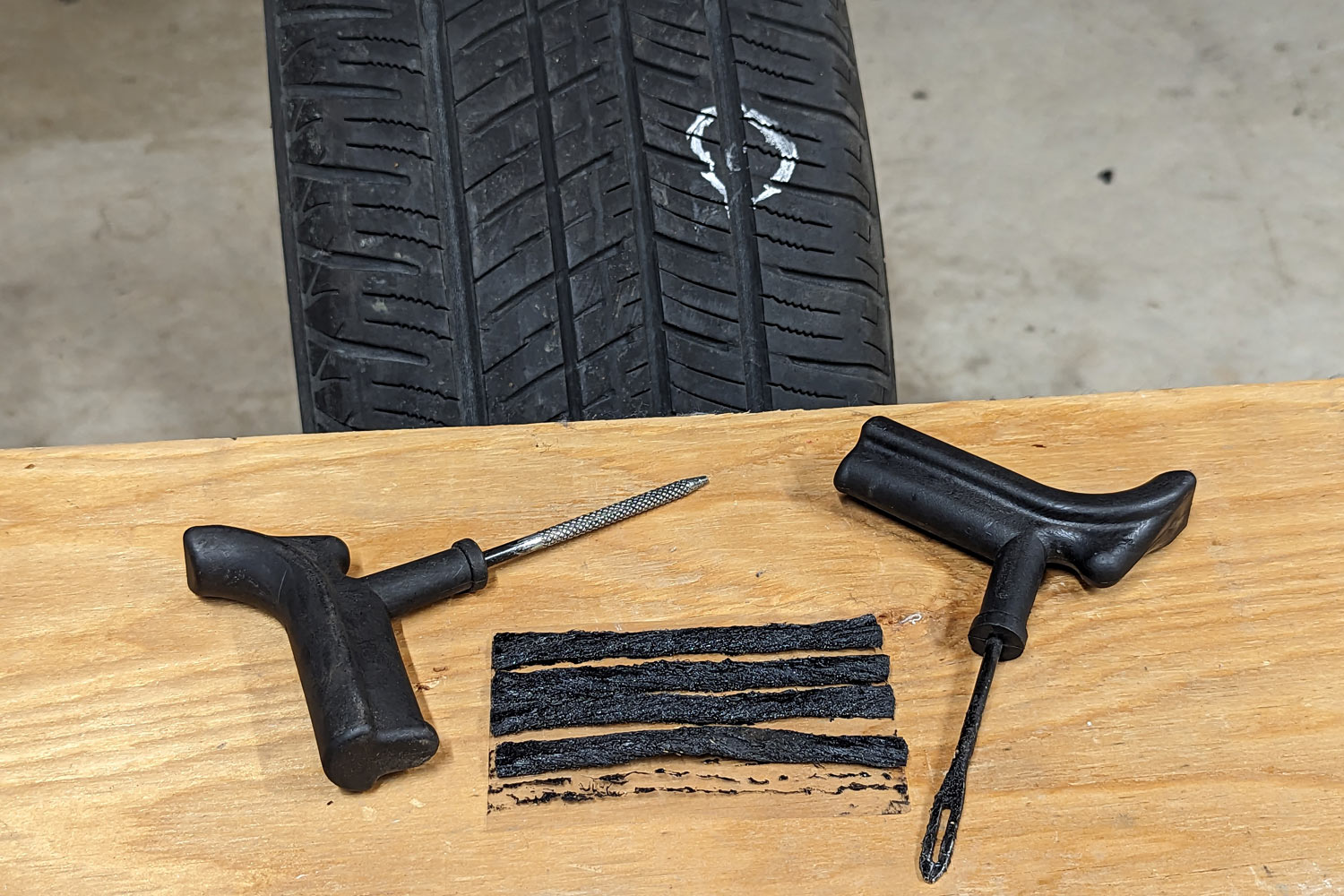Tire patch kit laid out on workbench next to damaged tire