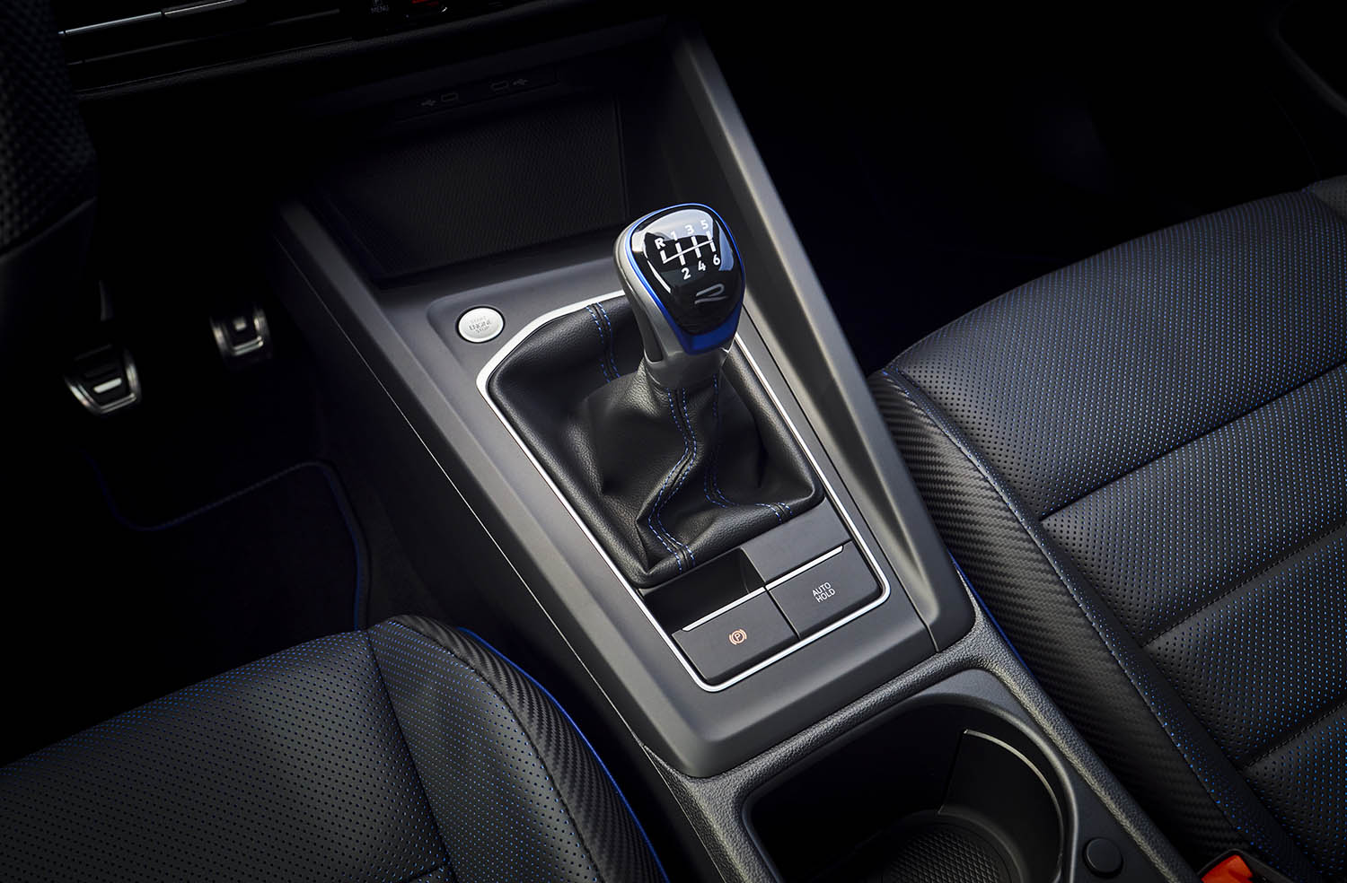 View of the center console in a 2022 Volkswagen Golf R with hill-start assist auto hold button below the shift knob.