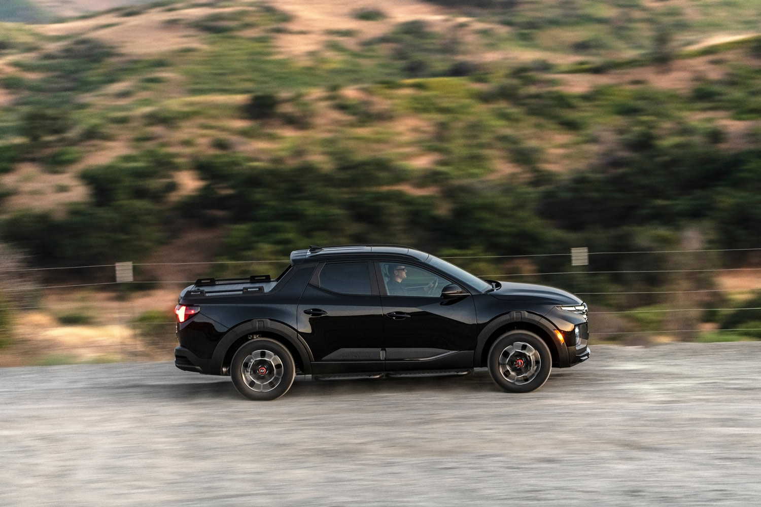 2023 Hyundai Santa Cruz in black driving along a mountainside on a gravel trail