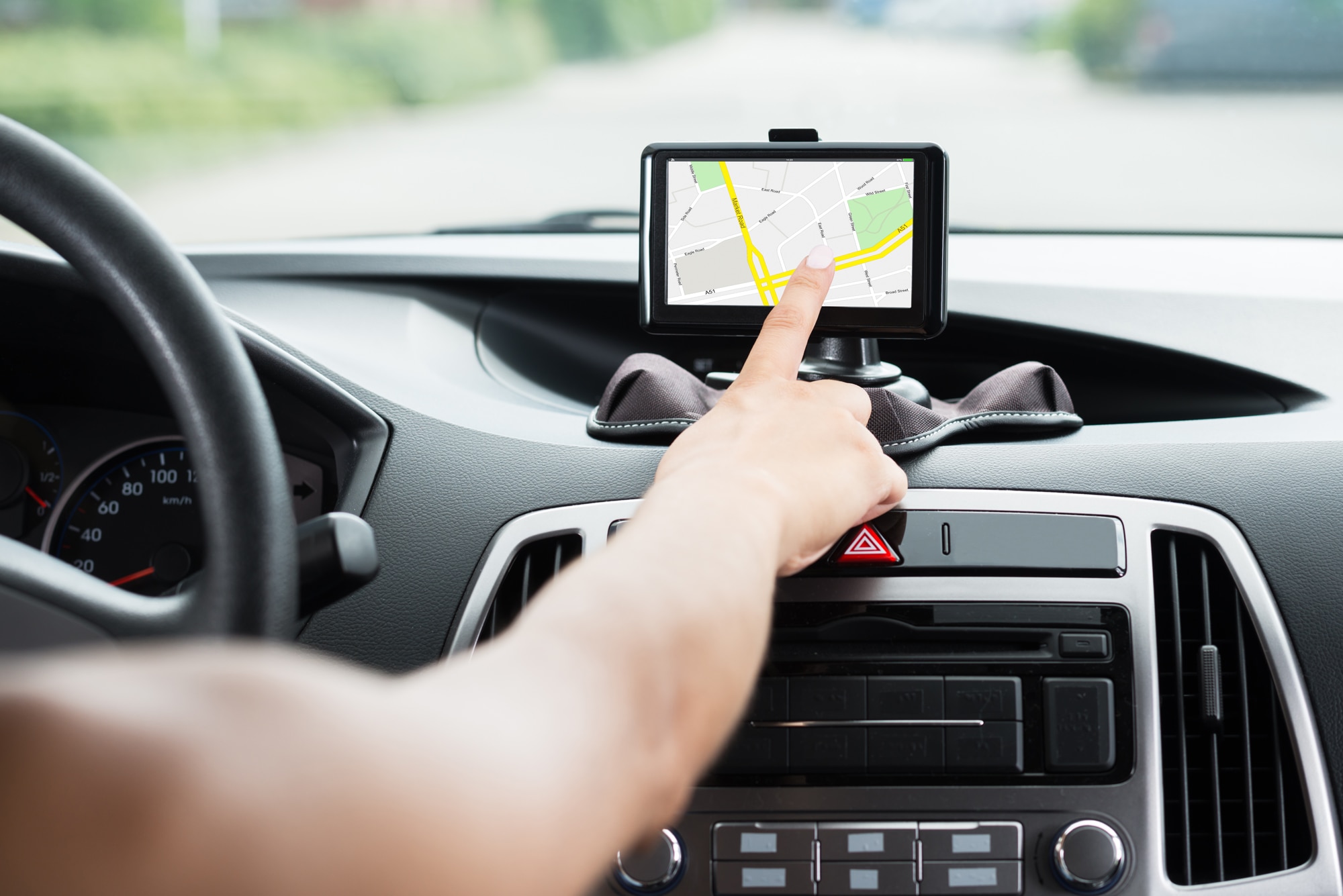 Close-up of woman's hand using mounted GPS navigation system in a car