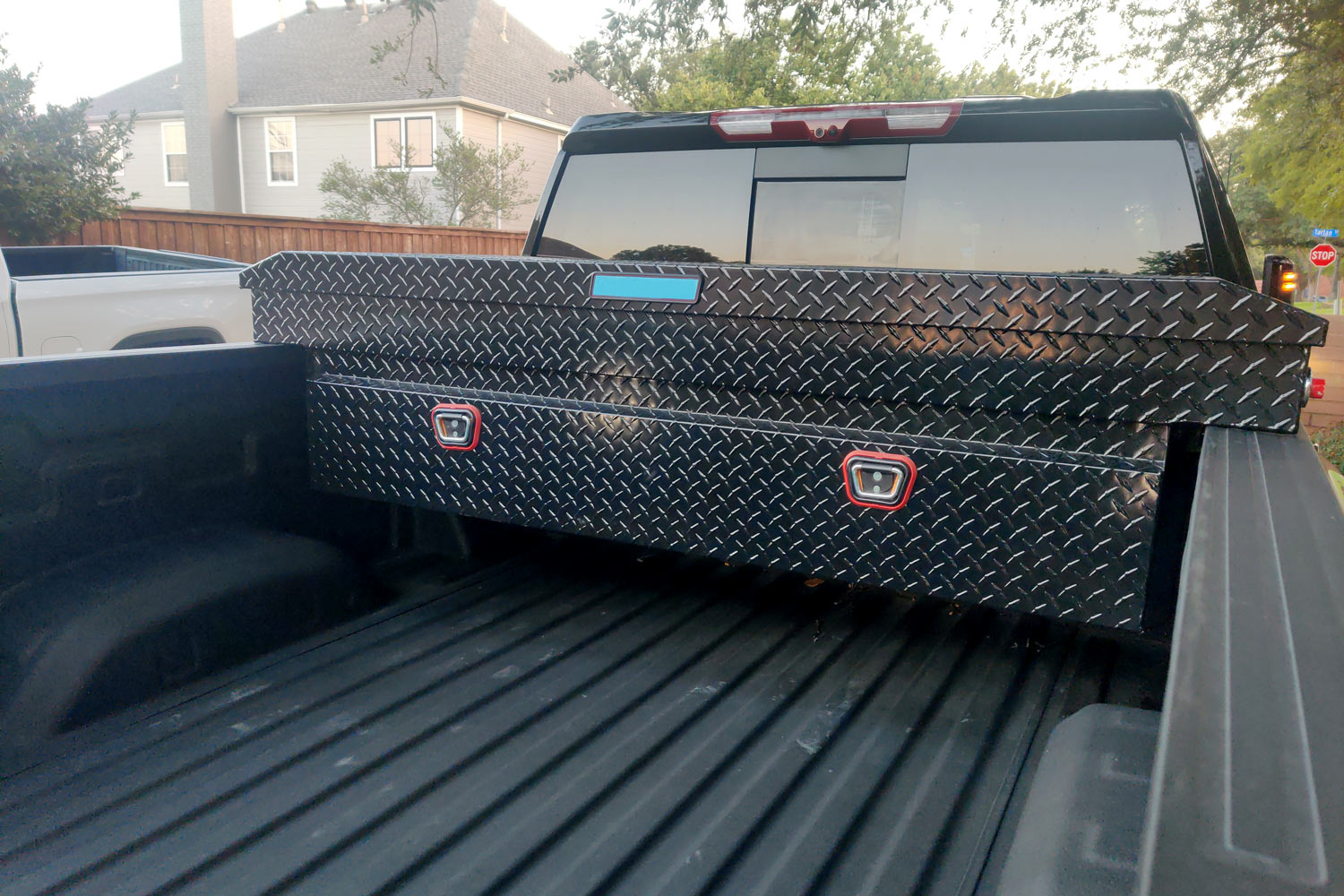 Black steel toolbox in bed of pickup truck.