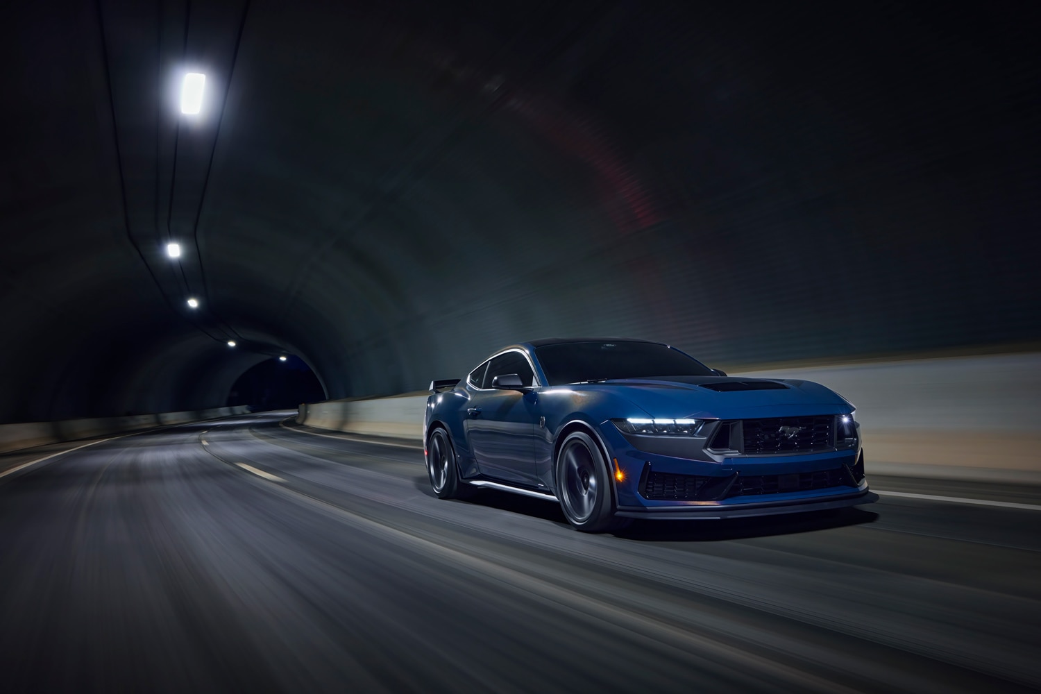 Blue 2024 Ford Mustang Dark Horse driving through a dark tunnel