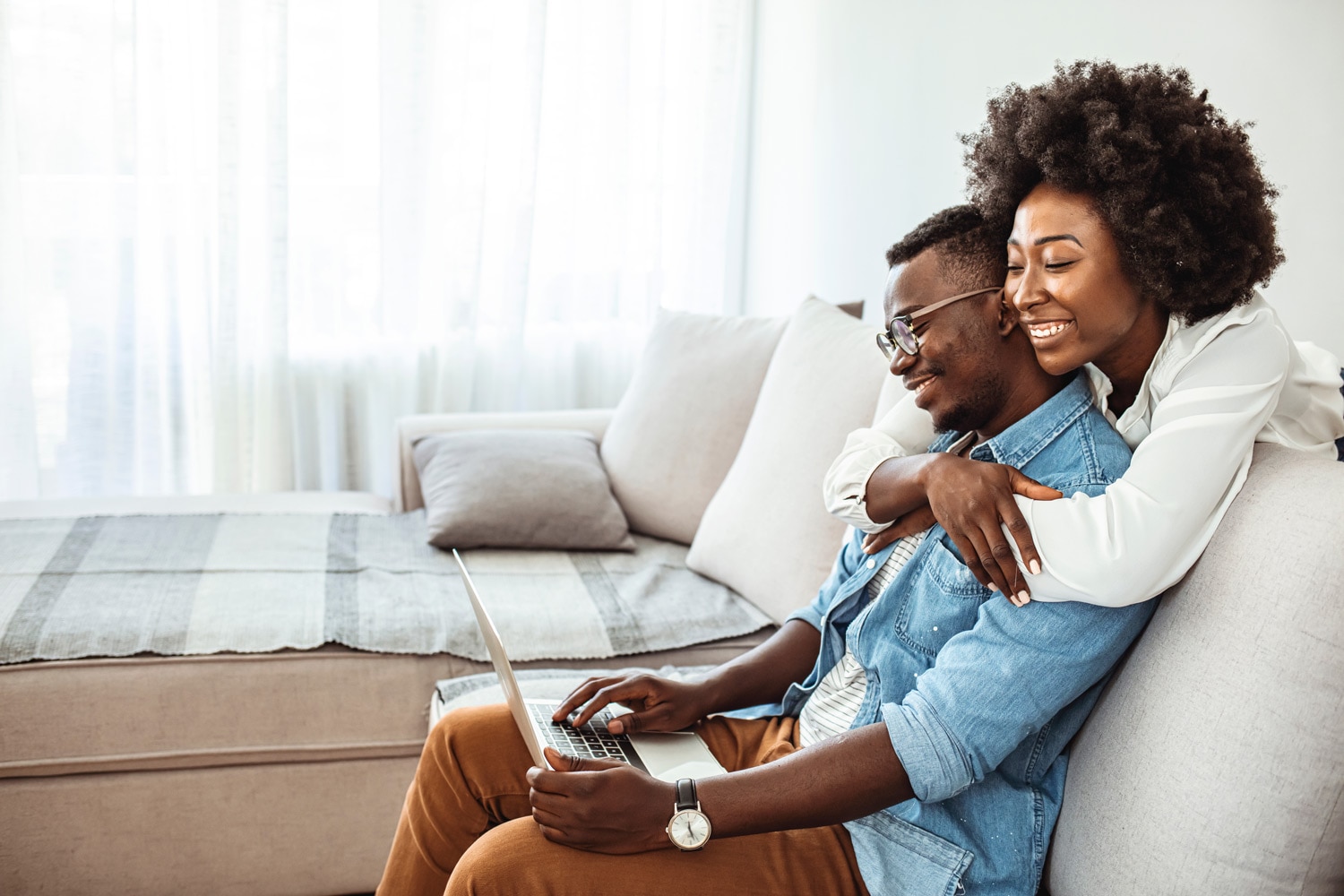 A happy couple looks at a laptop together and compares auto loan options