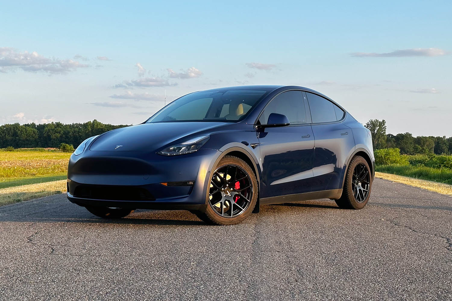 Front three-quarter view of 2023 Tesla Model Y in dark blue on paved road.
