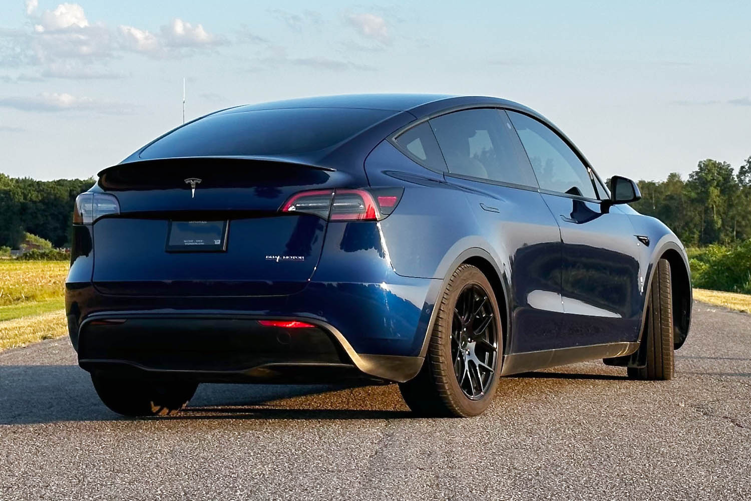 Rear three-quarter view of 2023 Tesla Model Y in dark blue on paved road.
