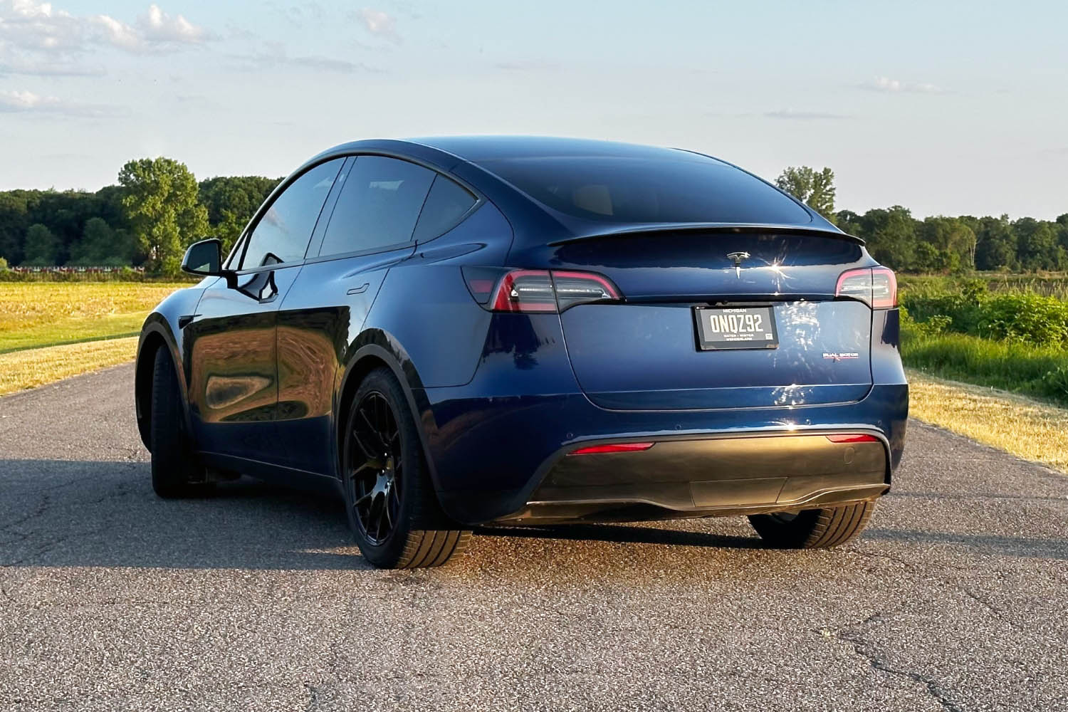 Rear three-quarter view of a 2023 Tesla Model Y in dark blue on pavement.