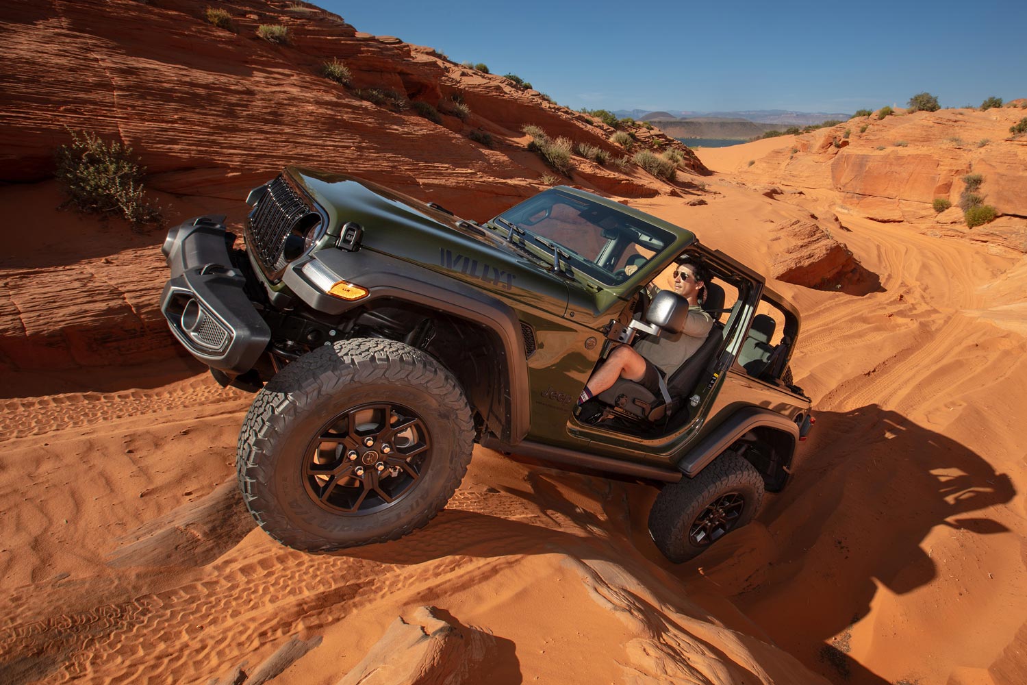 2023 Jeep Wrangler Willys in green driving up a steep obstacle