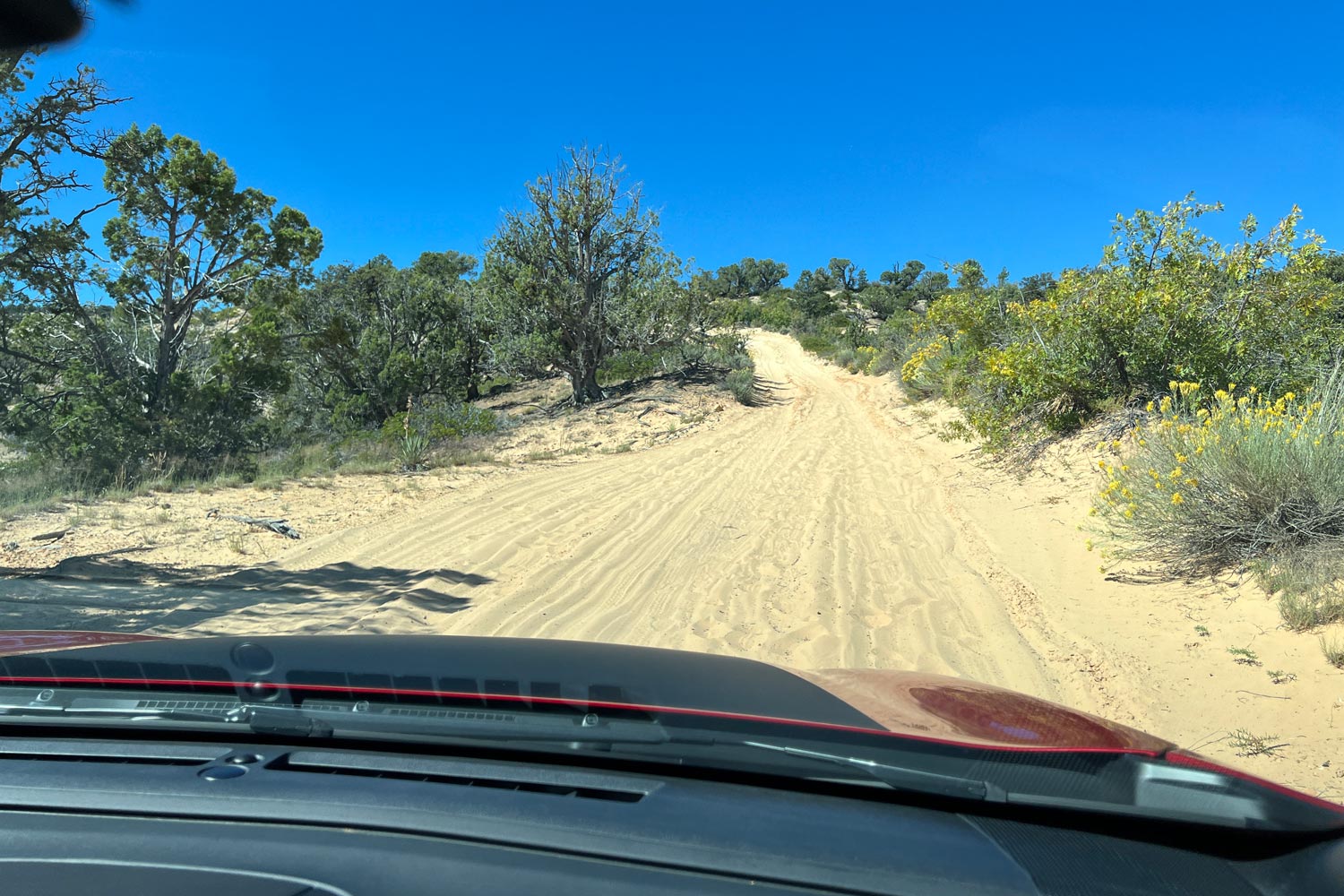 View of a sandy road out the windshield of a red 2024 Subaru Crosstrek Wilderness