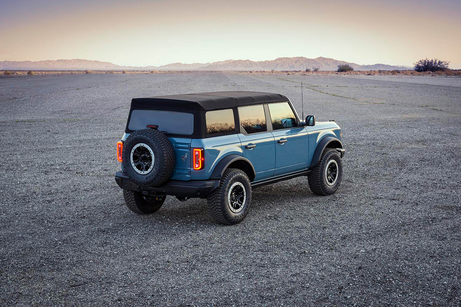 2021 Ford Bronco four-door Badlands in blue parked in a vast desert expanse, rear three-quarter view