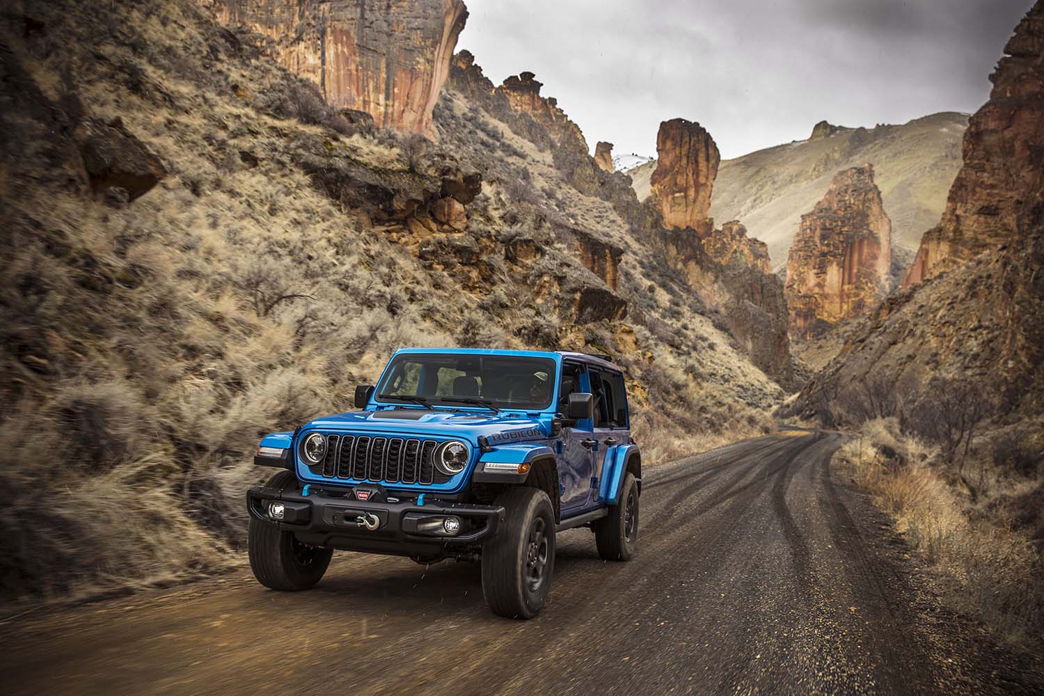 Jeep Wrangler Rubicon X4 in bright blue driving along canyon road
