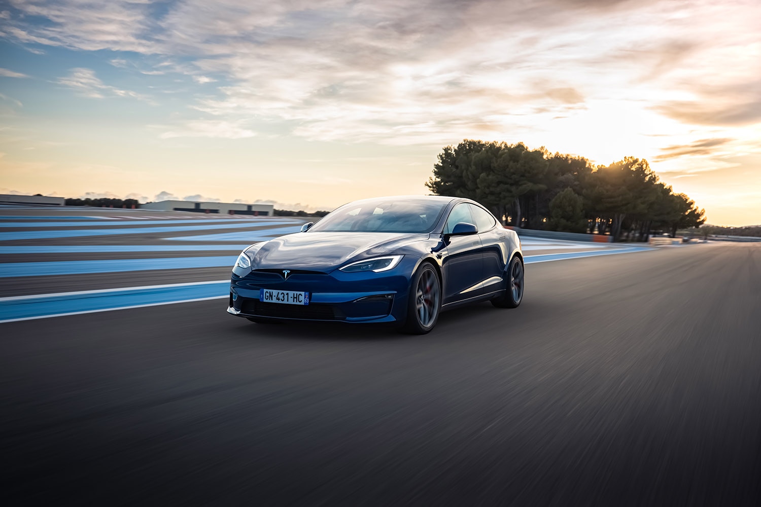 Tesla Model S in dark blue driving on paved road