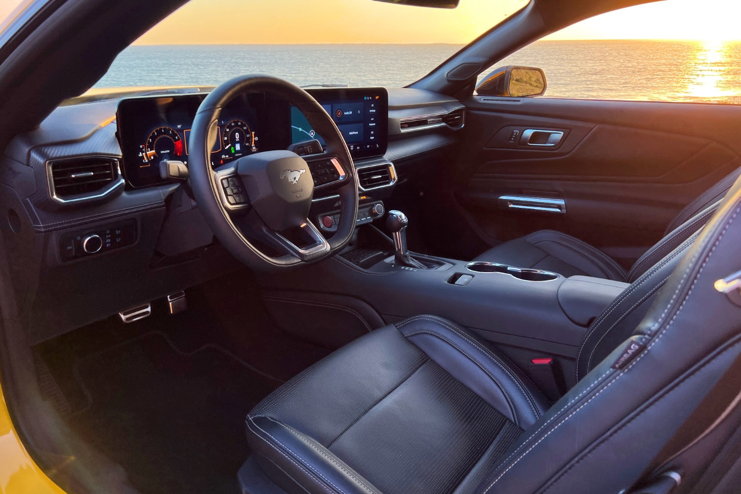2024 Ford Mustang interior, dashboard, and front seats against the sun setting into the Pacific Ocean