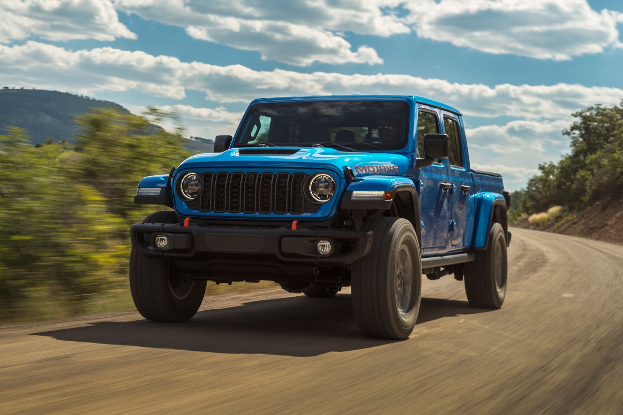 2024 Jeep Gladiator Mojave in blue driving down highway