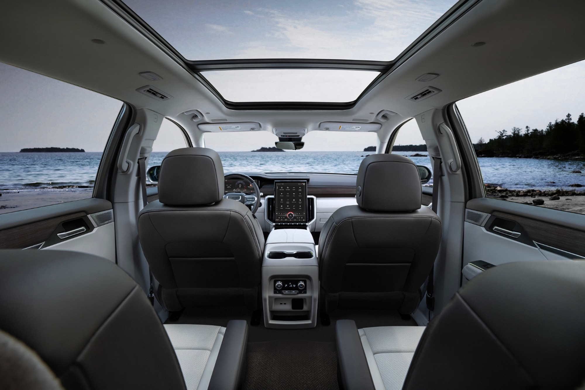2024 GMC Acadia Denali interior front rows with view of ocean and forest