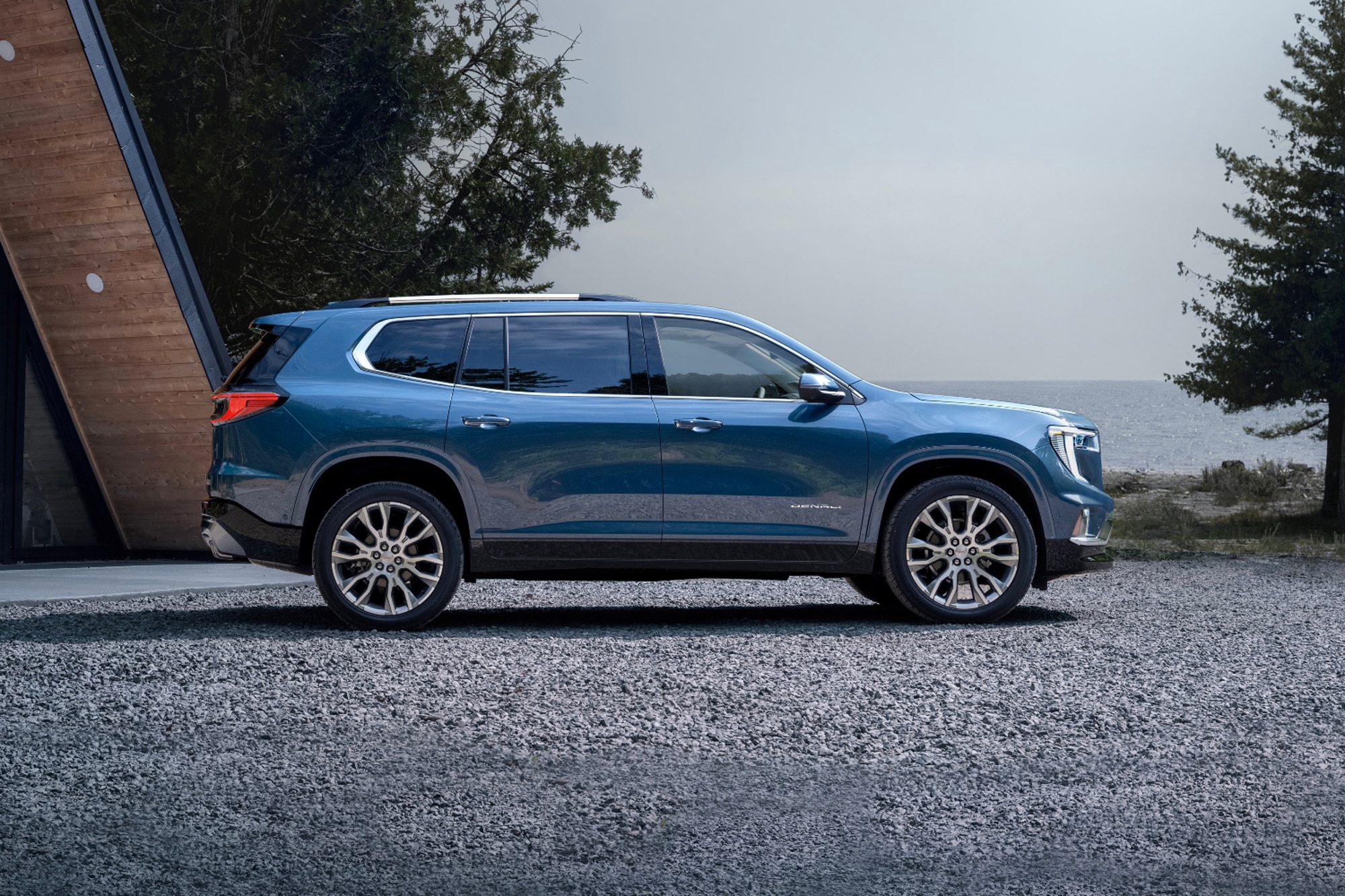 2024 GMC Acadia Denali in blue parked by the ocean outside a house