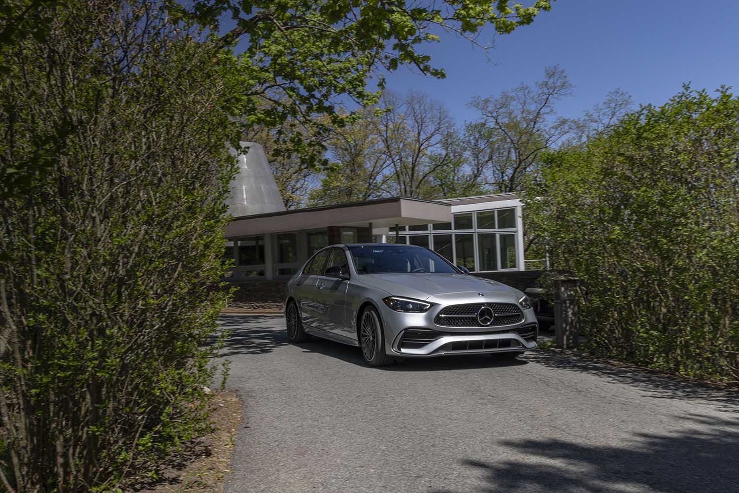 2022 Mercedes-Benz C-Class in silver parked in front of a building upon a pathway with bushes on both sides