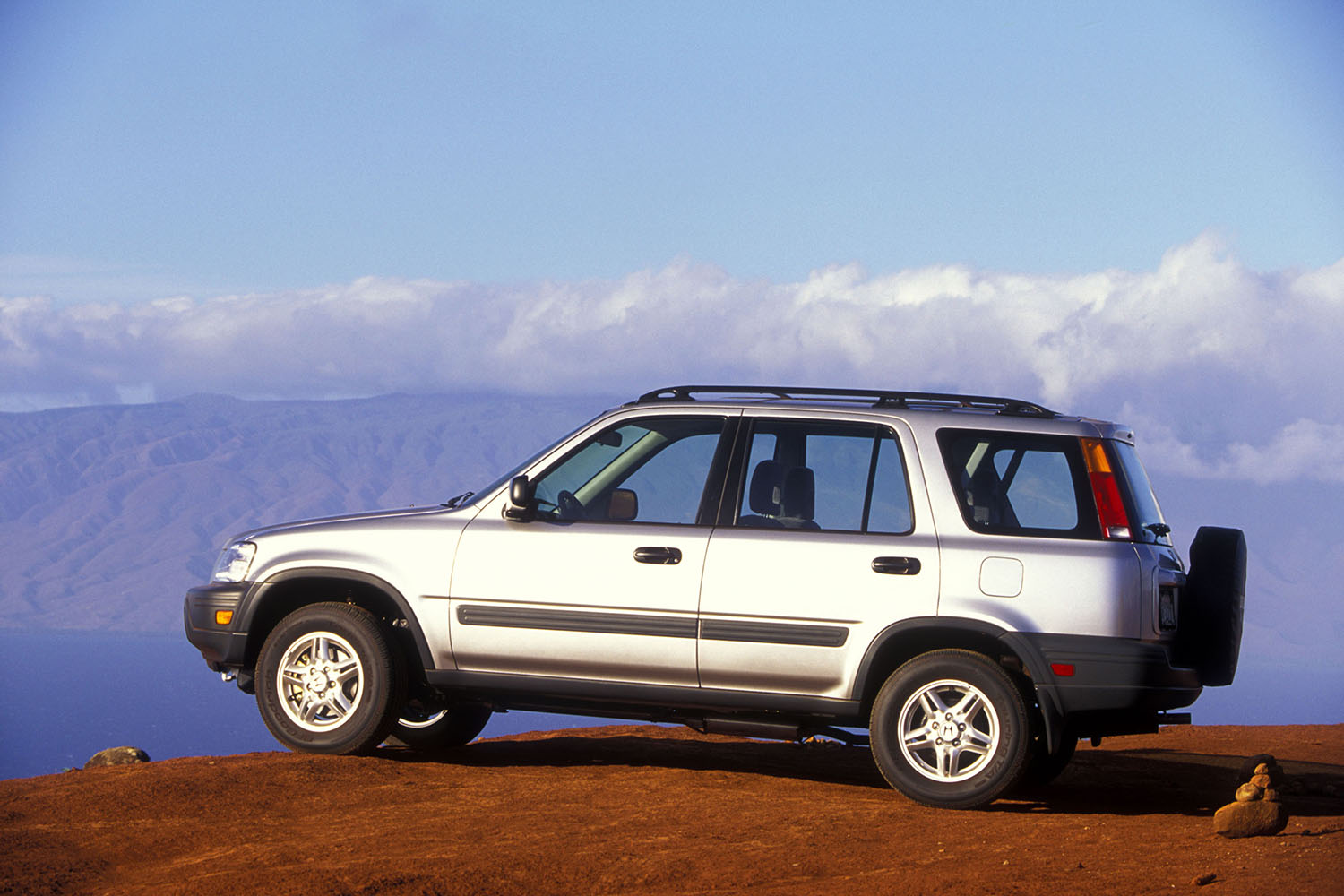 1997 Honda CR-V in silver parked on a cliff overlooking mountains and clouds.