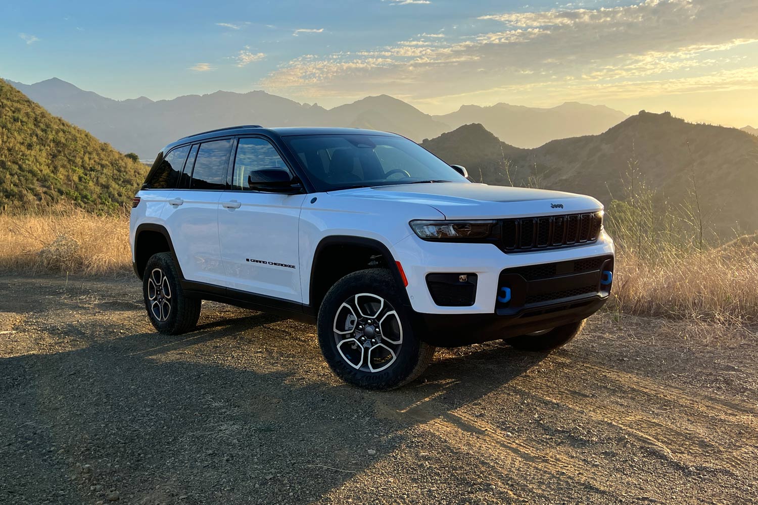 White 2023 Jeep Grand Cherokee 4xe Trailhawk parked on gravel.