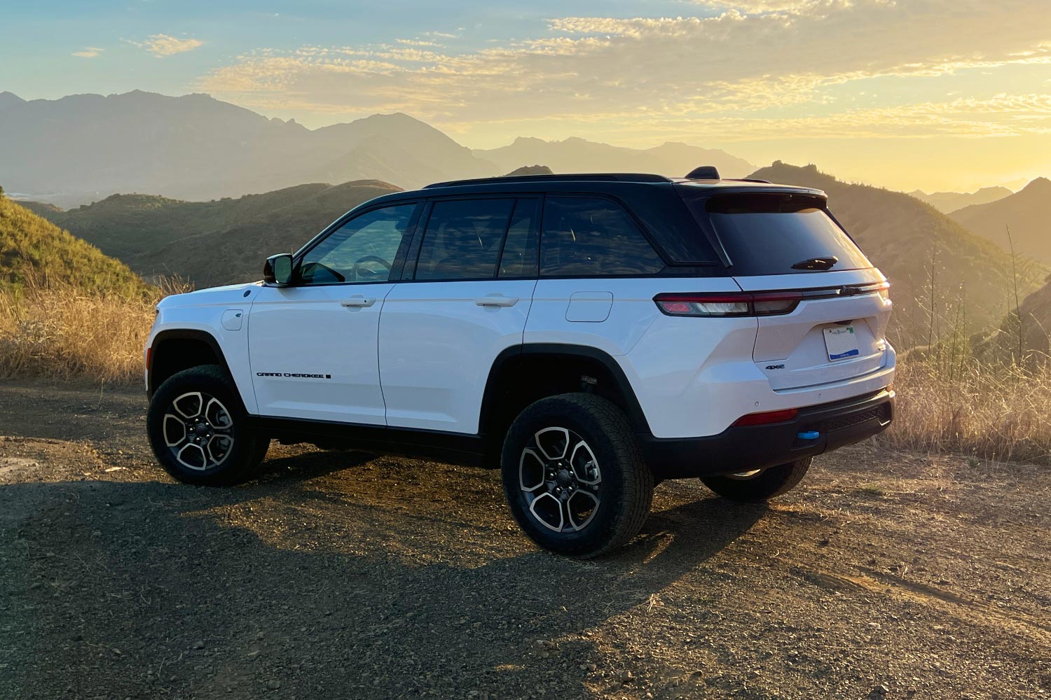 White 2023 Jeep Grand Cherokee 4xe Trailhawk parked on gravel.