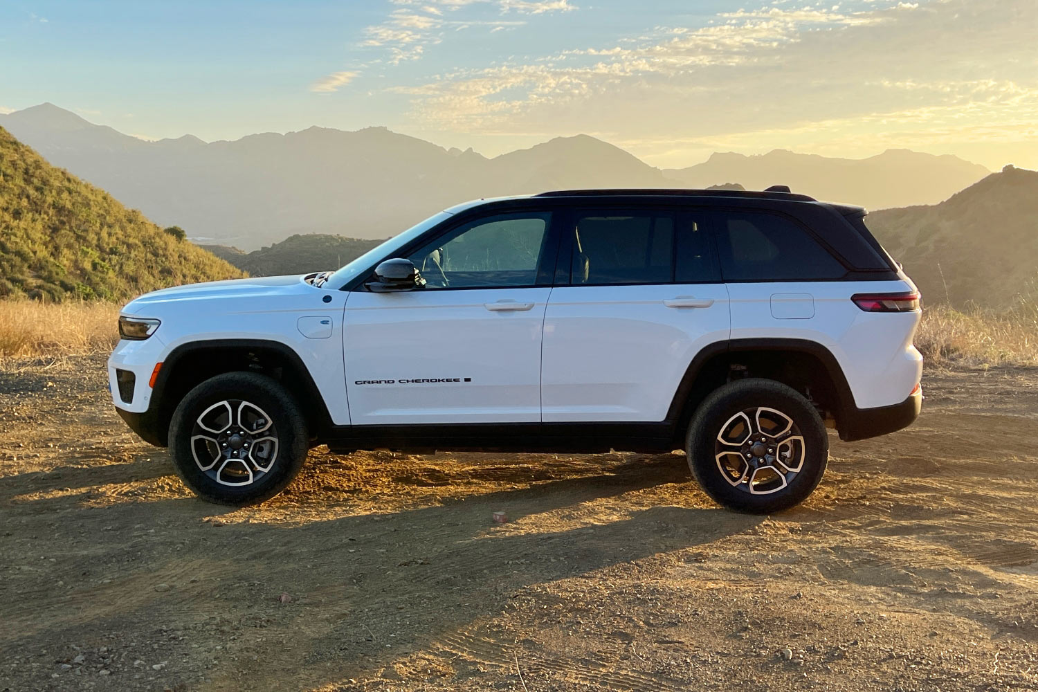 White 2023 Jeep Grand Cherokee 4xe Trailhawk parked off-road.