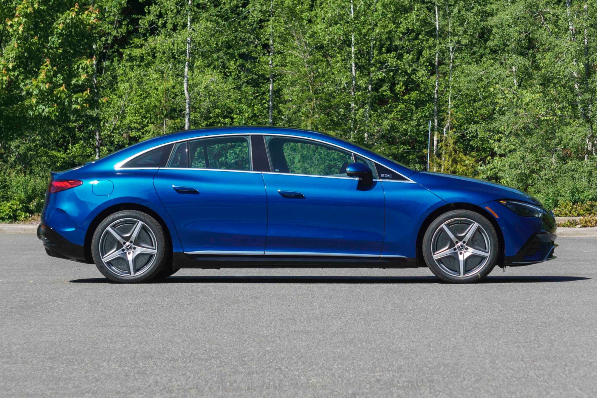 2023 Mercedes-Benz EQE Sedan in Starling Blue side view parked next to the woods